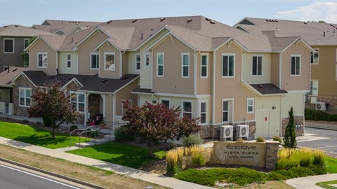 A row of houses with a sign in front that says Enclave.
