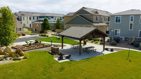 A gazebo sits in the middle of a grassy area with a picnic table and benches.