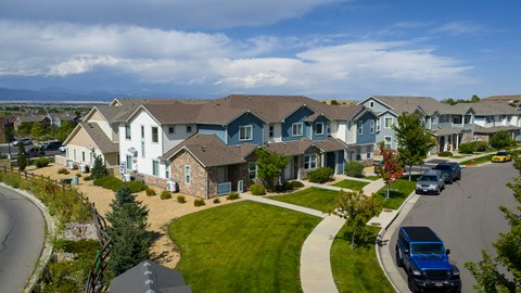 A blue truck is parked on the street in front of a house.