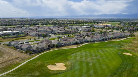 A golf course with a green and a sand trap.