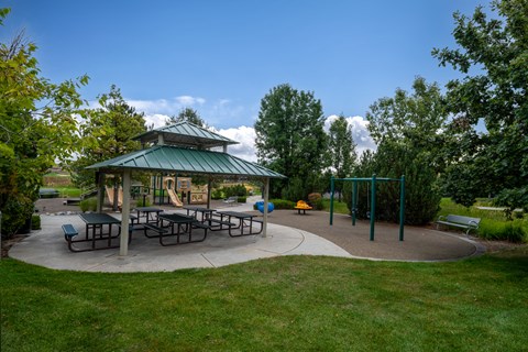 A gazebo is surrounded by a circular concrete patio with picnic tables.