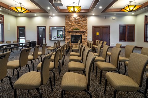 A room with a stone fireplace and rows of chairs.