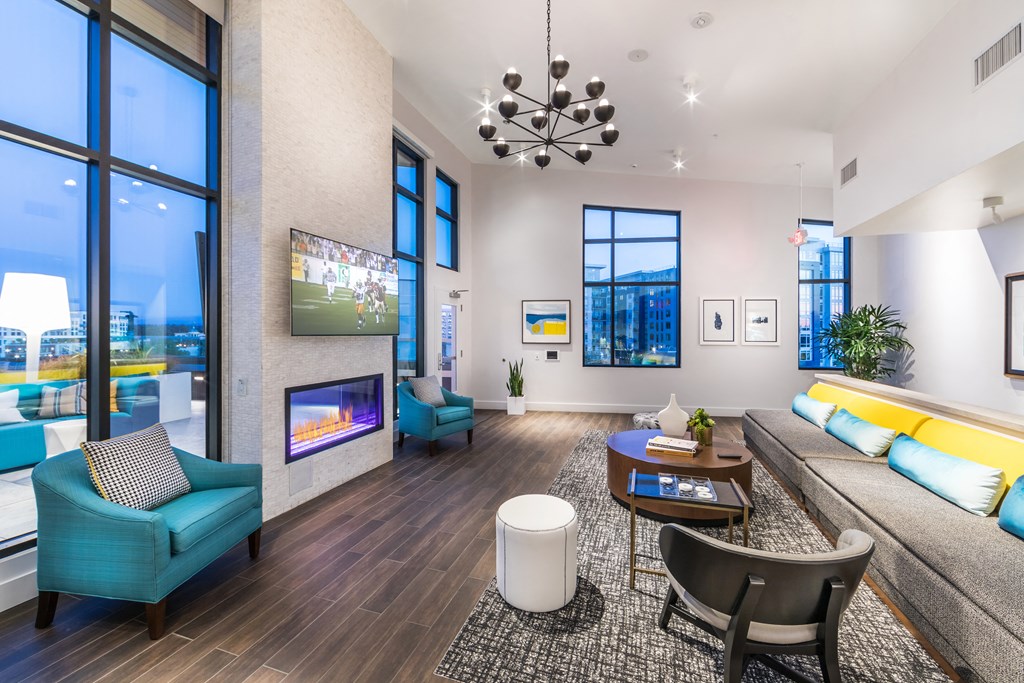 a living room with couches a table and a fireplace   and large windows