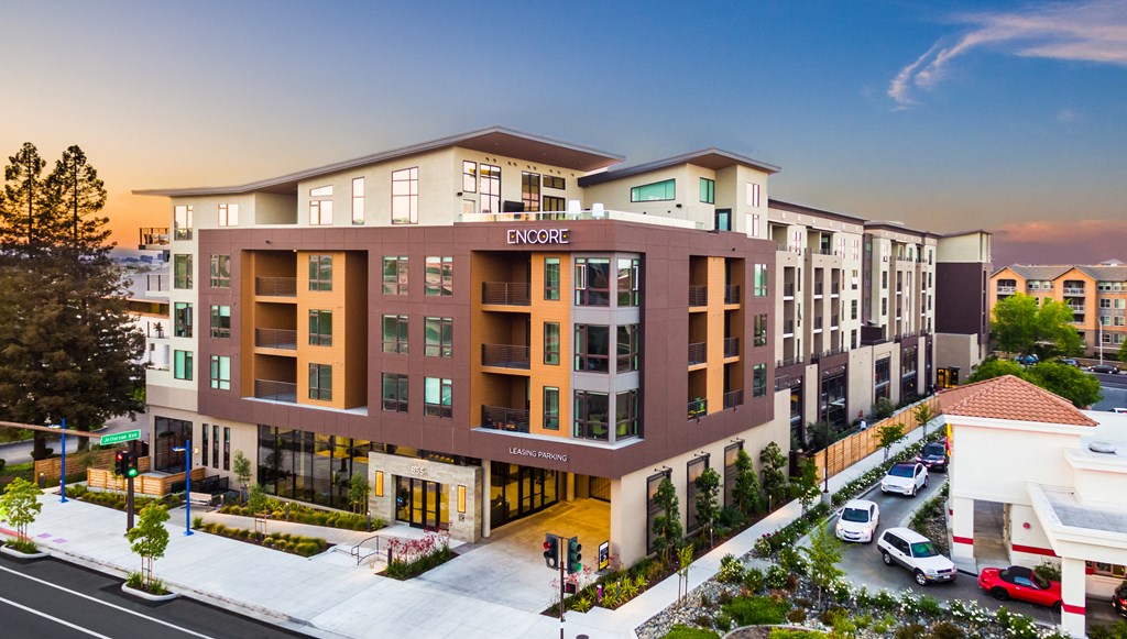a rendering of an apartment building with cars parked in front of it