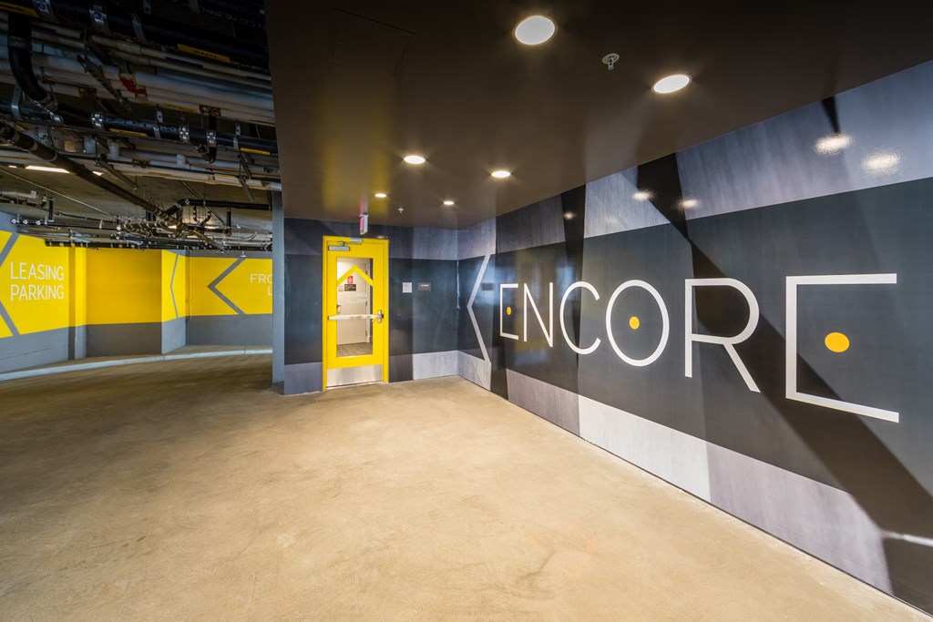 a lobby with a yellow door and a blue wall with a large logo on it