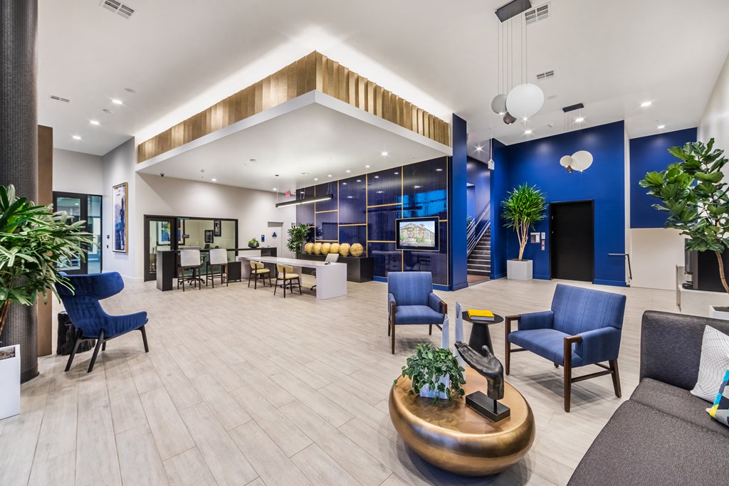 the lobby of a hotel with blue chairs and a reception desk