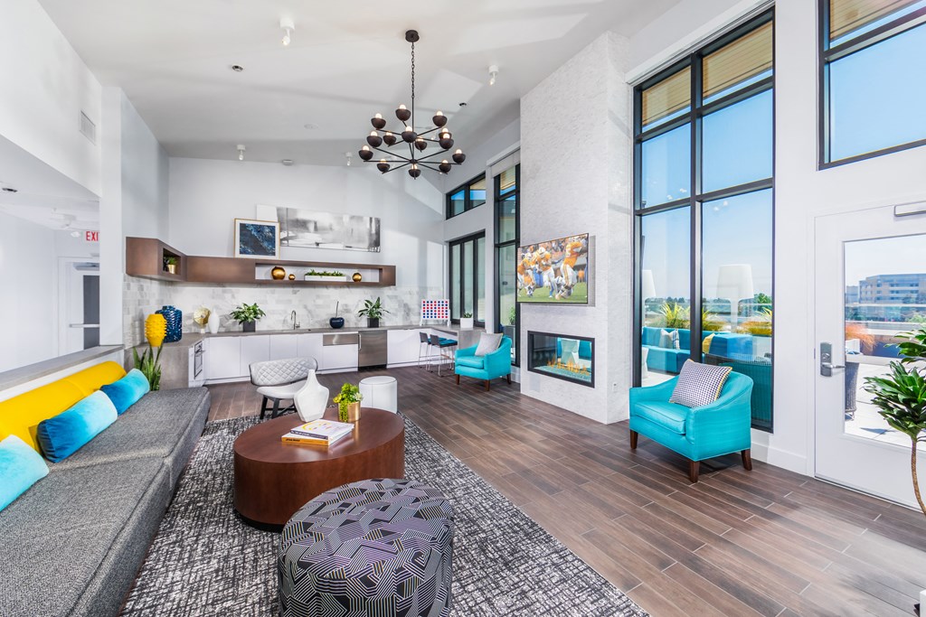 a living room with blue and yellow furniture and large windows