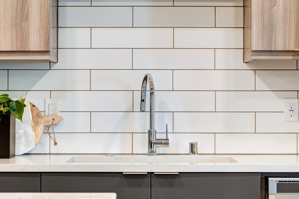 a white kitchen with white subway tiles and a stainless steel sink