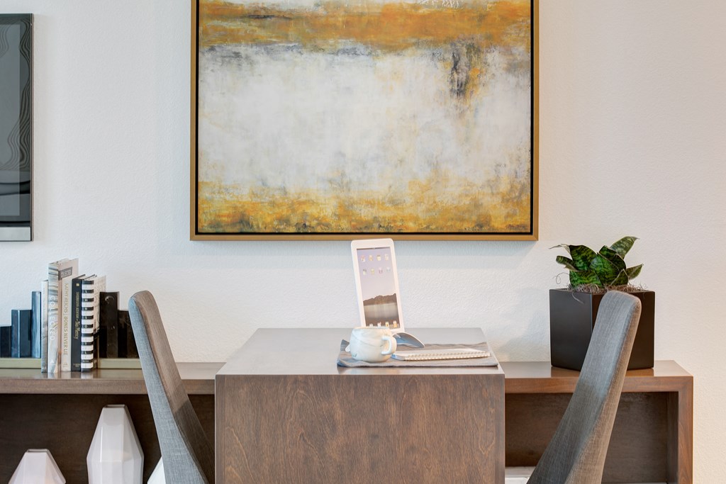 a desk with a laptop on it in a room with a table and chairs