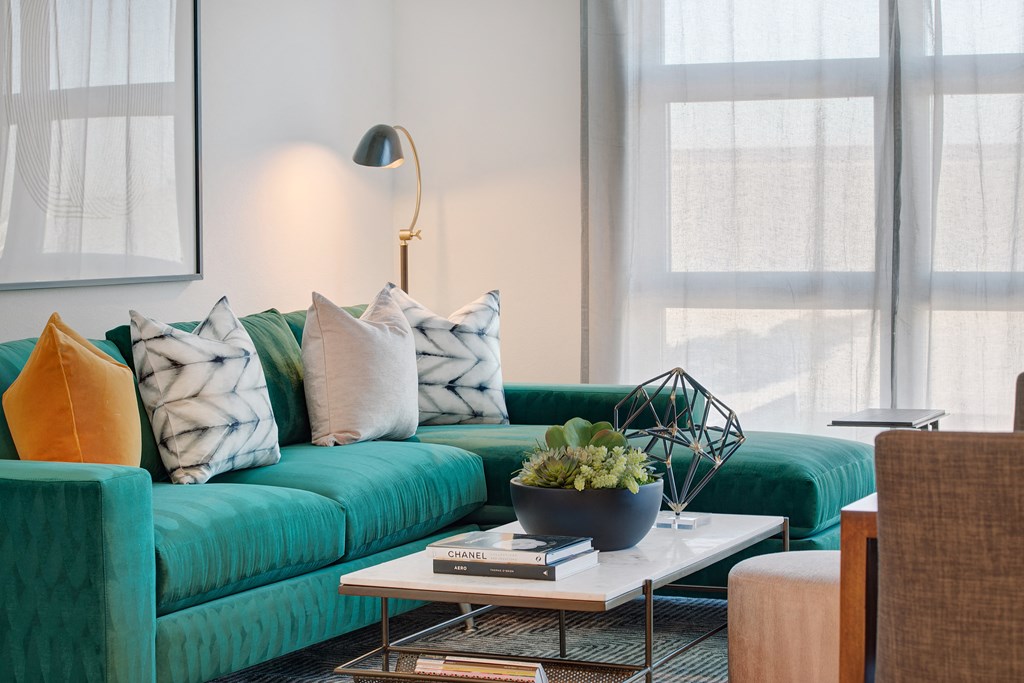 a living room with a green couch with pillows and a coffee table