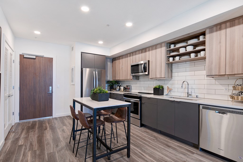 a kitchen with stainless steel appliances and a table with three chairs