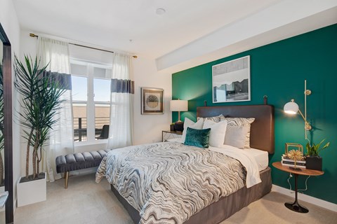 a bedroom with a bed and a green wall and a window