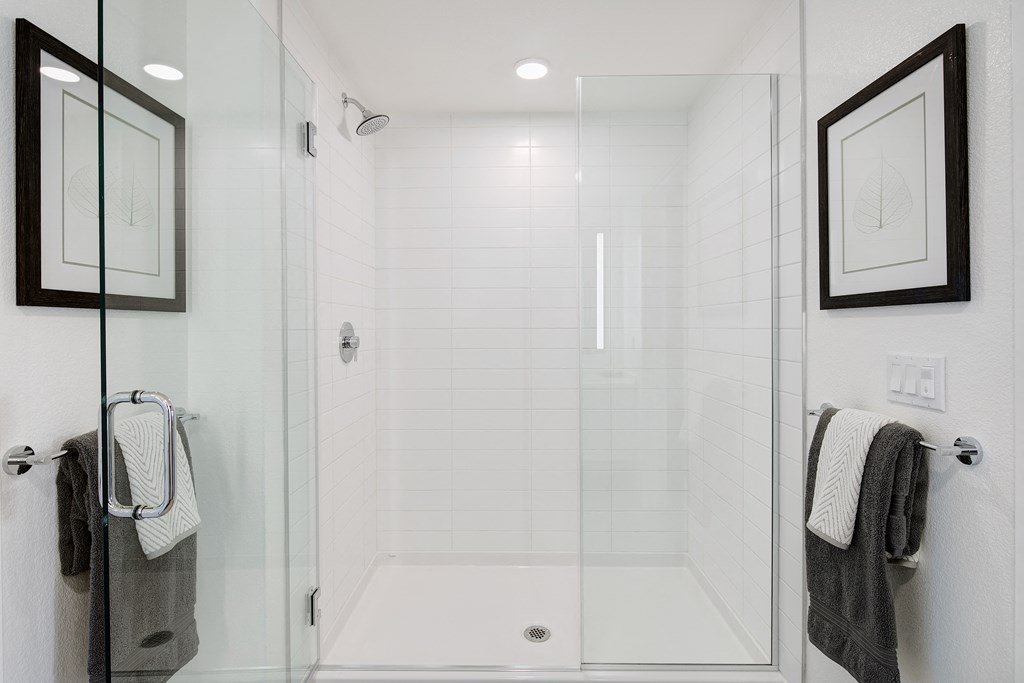 a white bathroom with a shower and two towels on the rack