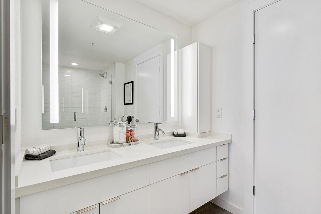 a white bathroom with two sinks and a mirror