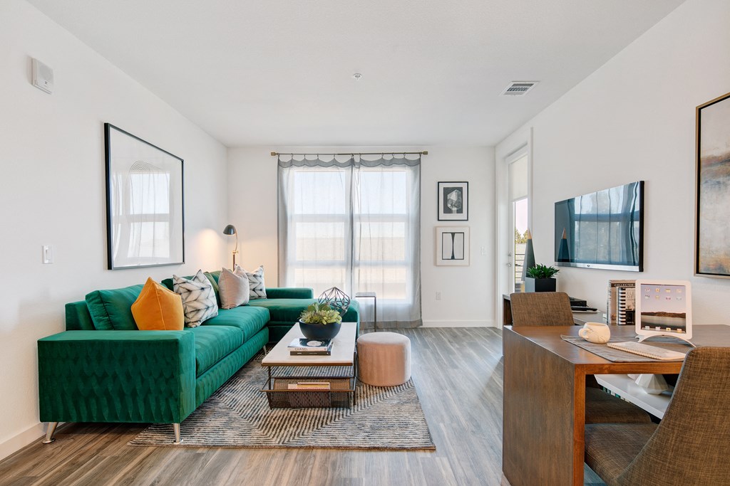 a living room with a green couch and a large window