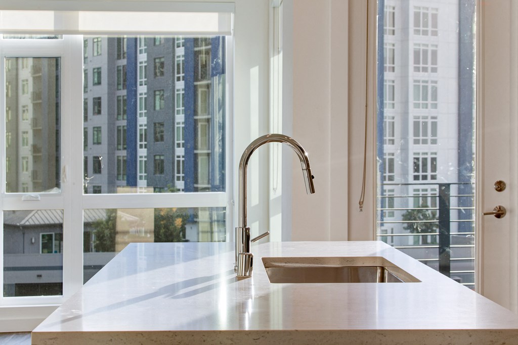 a kitchen counter with a faucet in front of a window