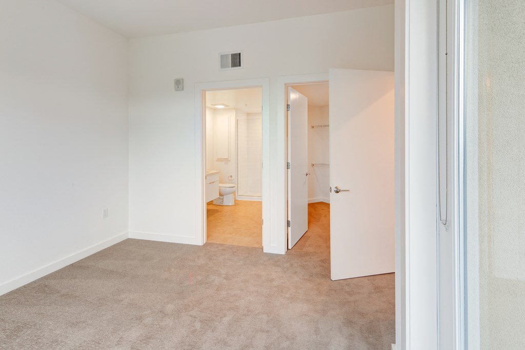 a bedroom with a carpeted floor and a door to a bathroom