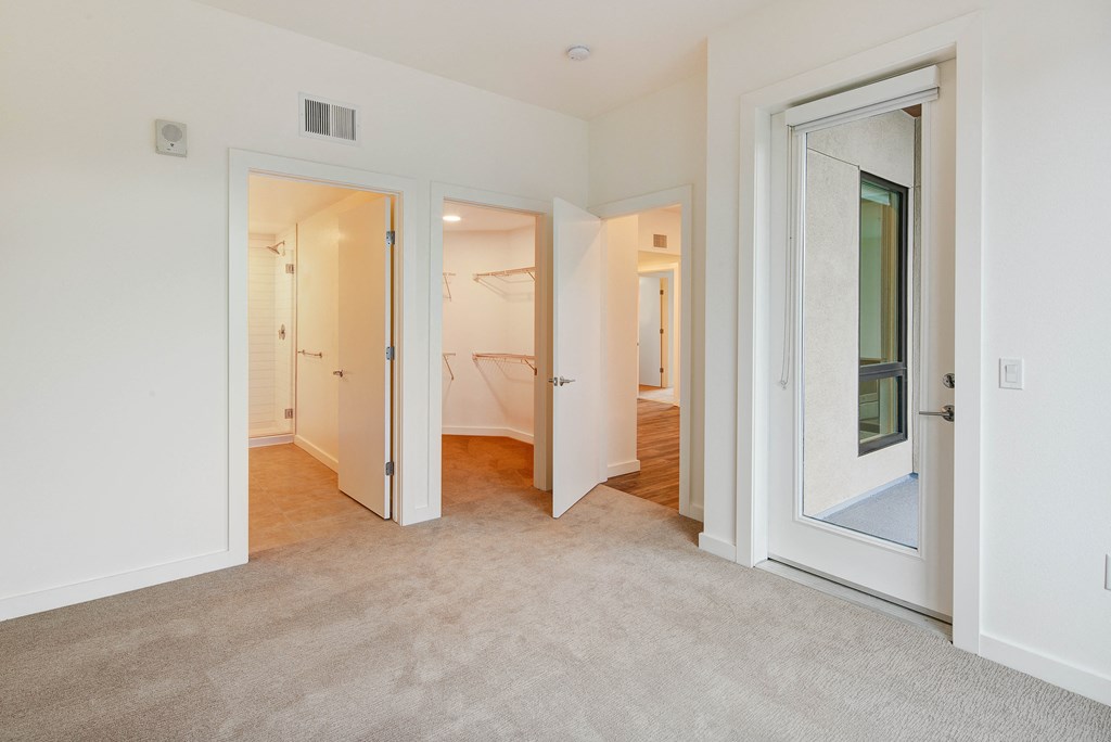a bedroom with a door to a bathroom and a living room