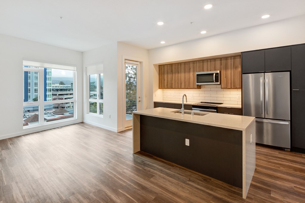 a kitchen with a large island and a stainless steel refrigerator