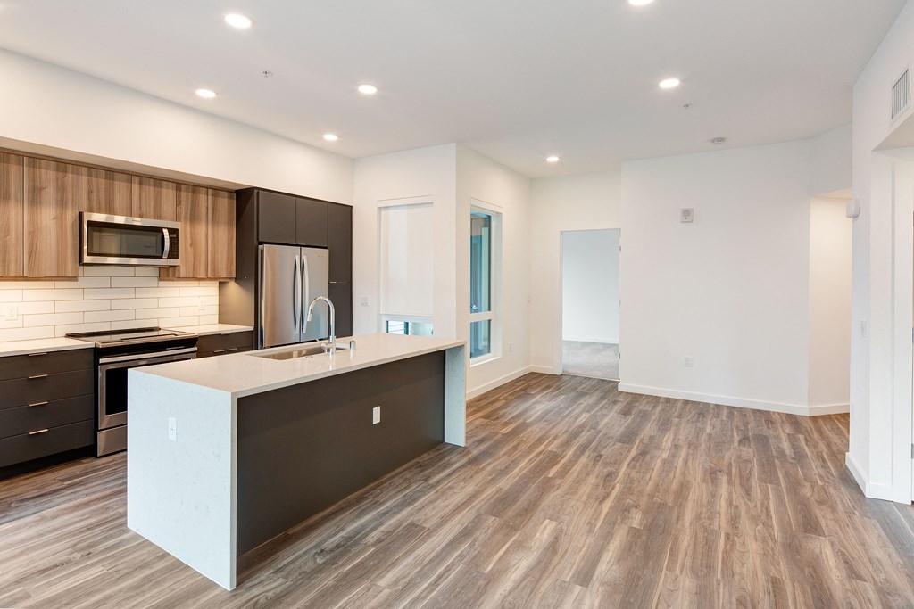 an open kitchen and living room with a large counter top in a new home