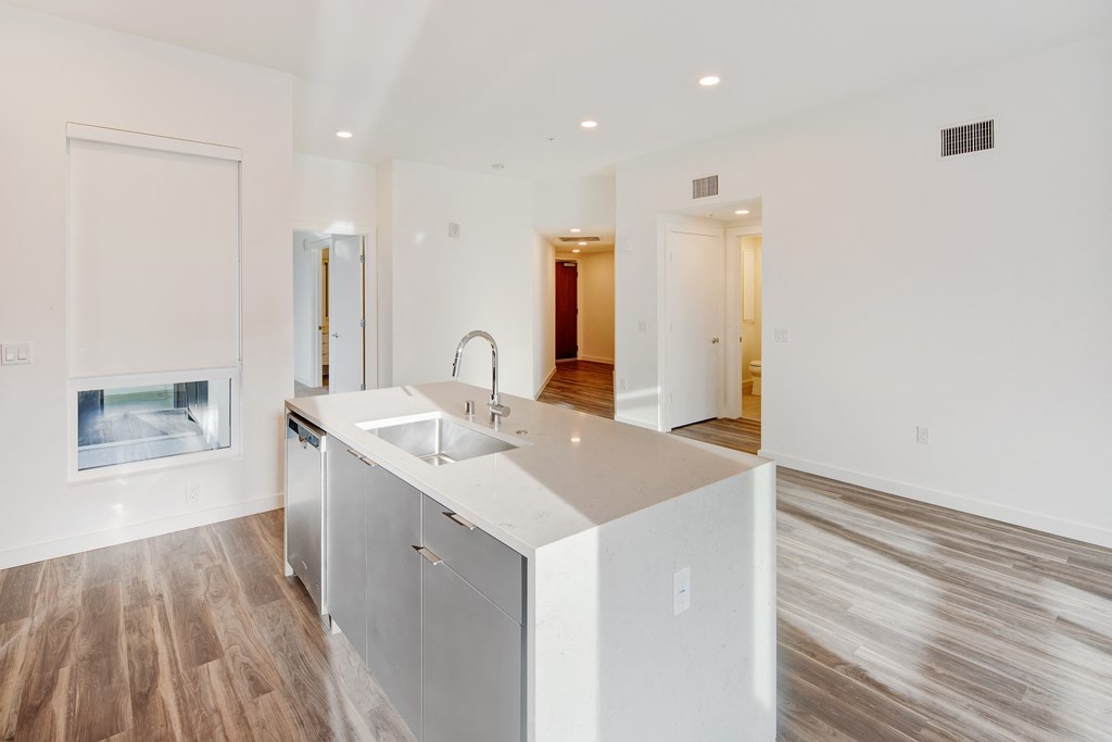 a large white kitchen with a sink and a white counter top