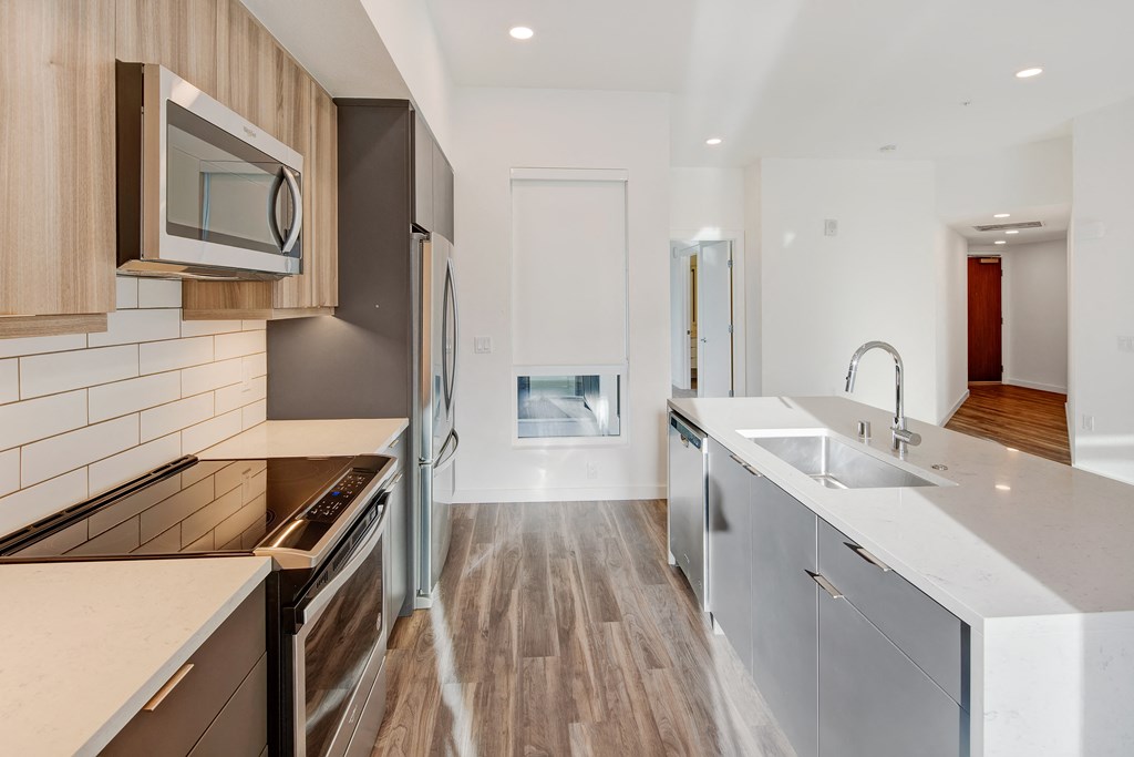 a renovated kitchen with white countertops and stainless steel appliances