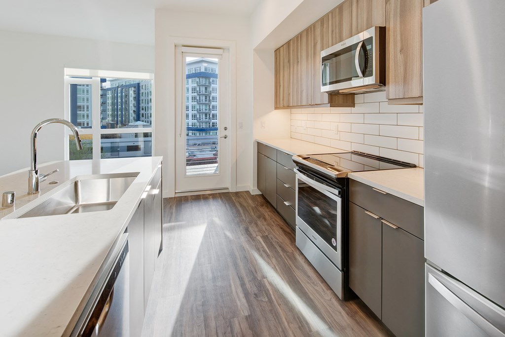 an empty kitchen with stainless steel appliances and a window