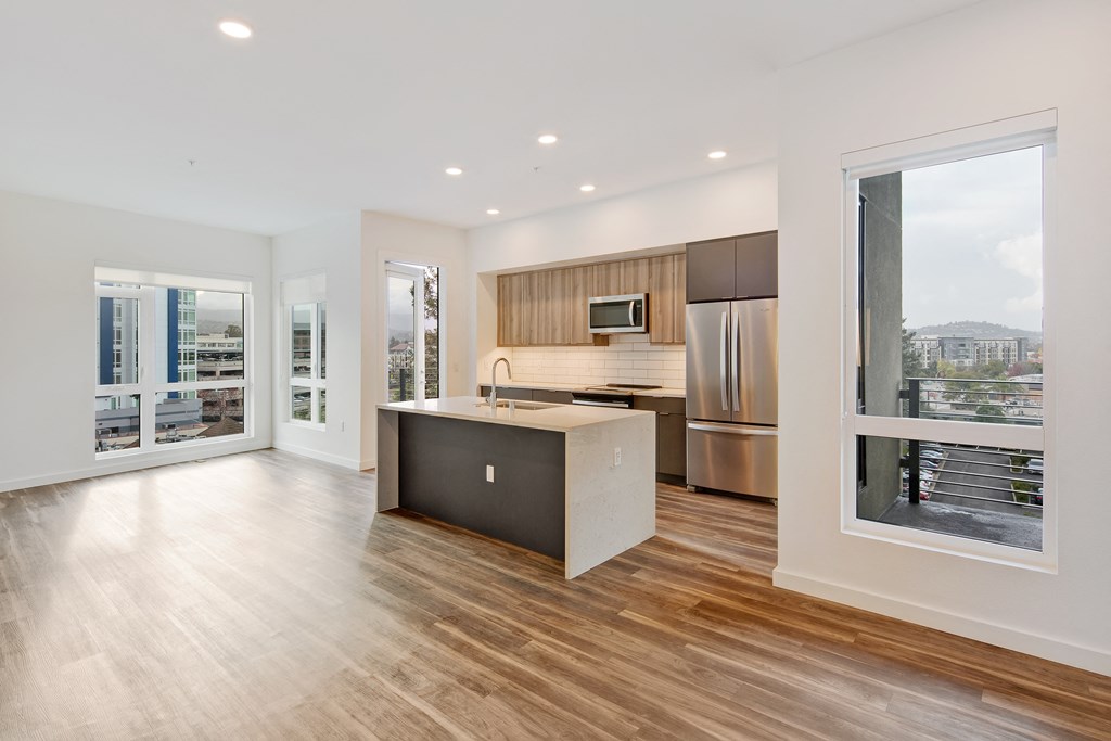 a living room with a kitchen and a door to a balcony