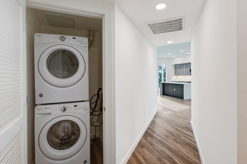 a front loading washer and dryer in a laundry room with a kitchen