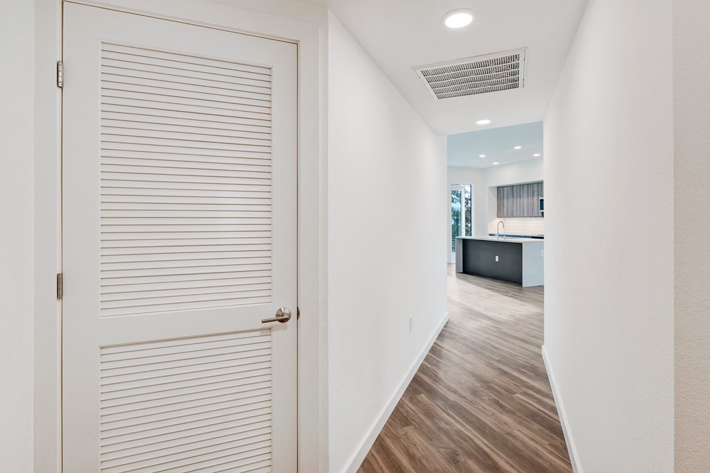 a white door leading into a hallway with a kitchen