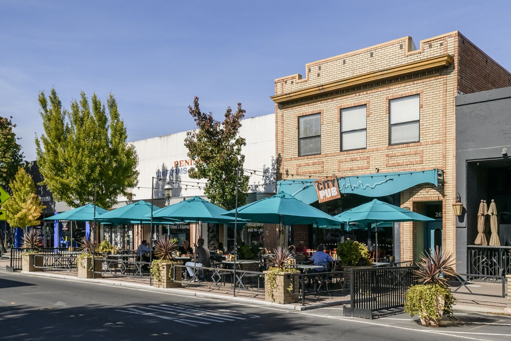 a street view of a restaurant with umbrellas on the sidewalk