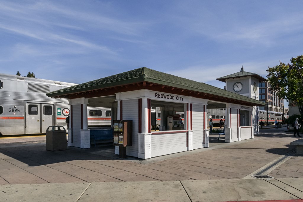 a small train station with a clock tower on the side of a street