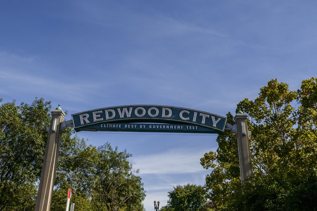 a sign that reads redwood city against a blue sky