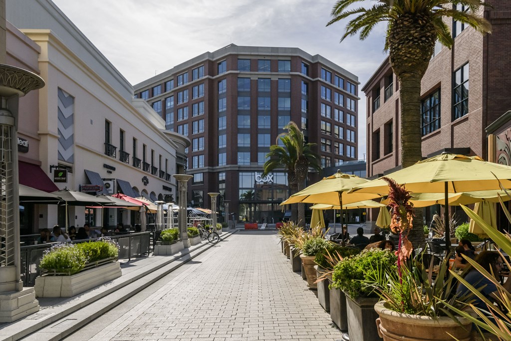 a city street with umbrellas and cafes and tall buildings