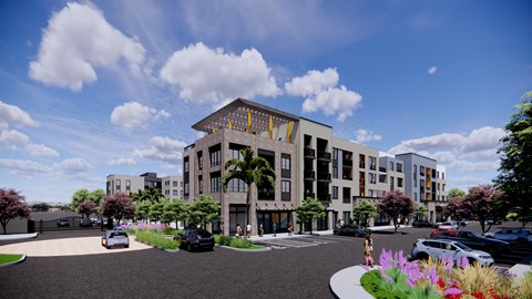 A modern building with a yellow logo on the front is surrounded by trees and flowers.