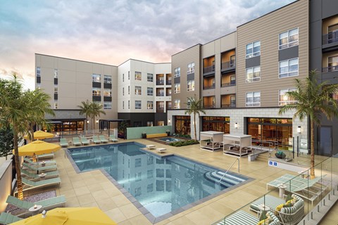 A large swimming pool is surrounded by sun loungers and umbrellas.