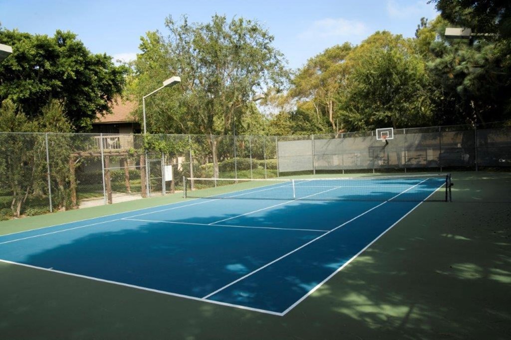 a tennis court with a fence and a basketball hoop on it