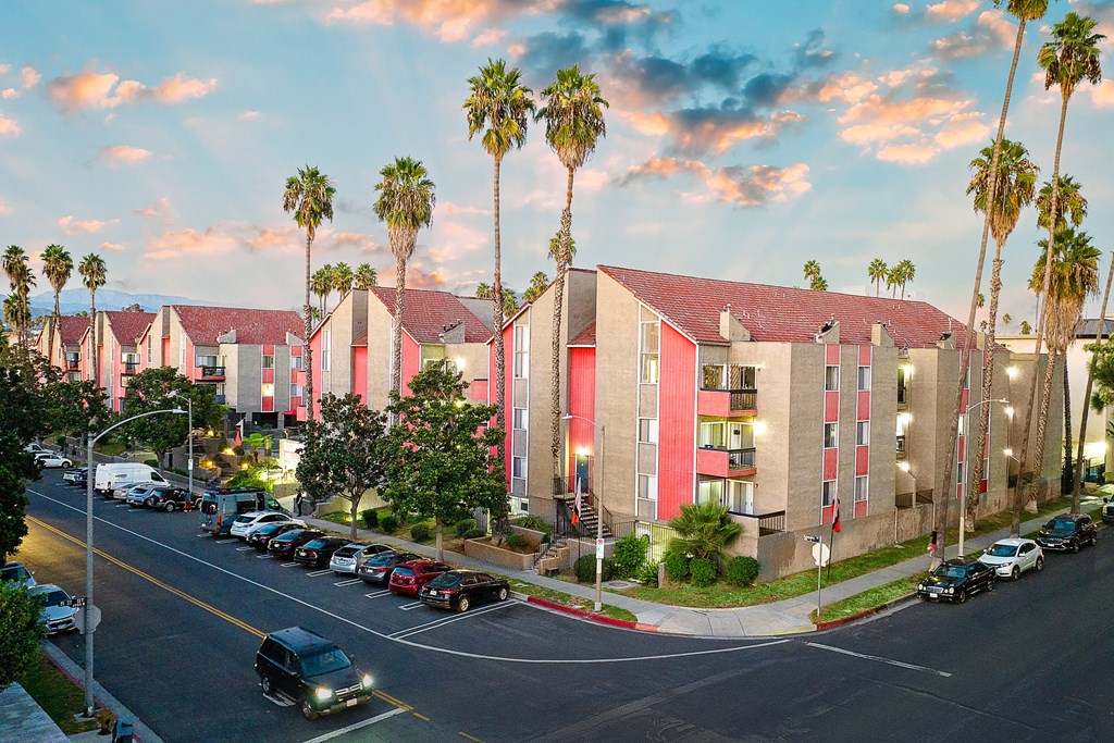 a city street with a row of buildings and palm trees