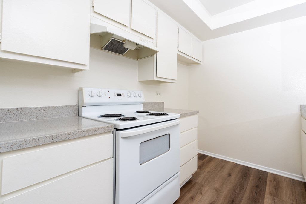 A white stove and oven in a kitchen with white cabinets.