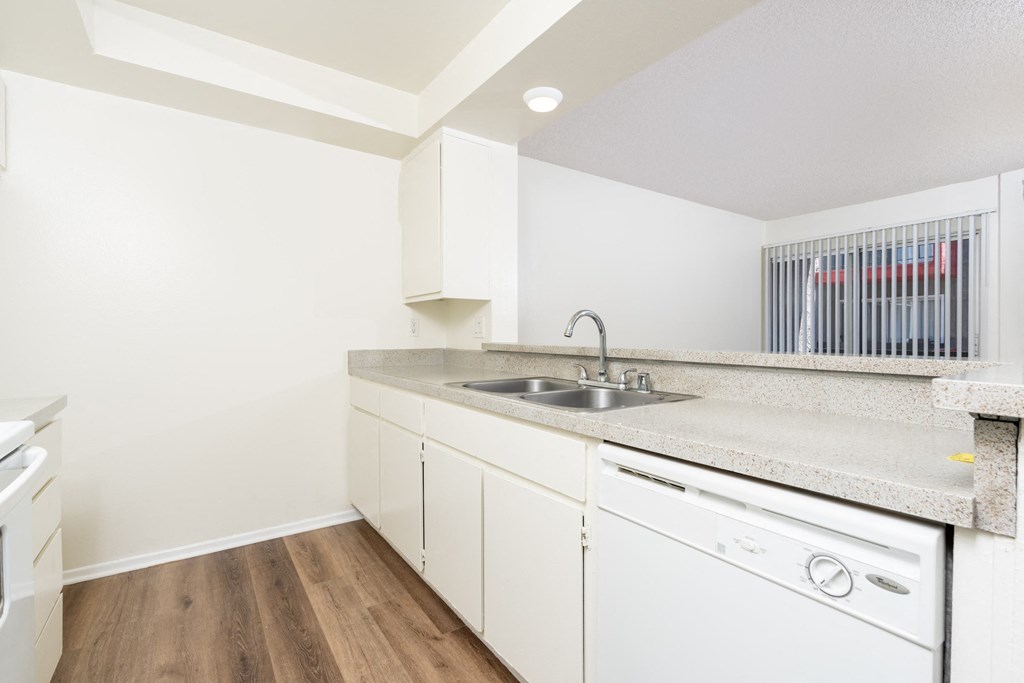 A kitchen with white cabinets and a white dishwasher.