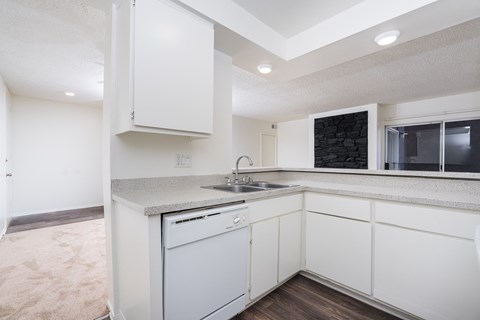 a kitchen with white cabinets and a sink and a window
