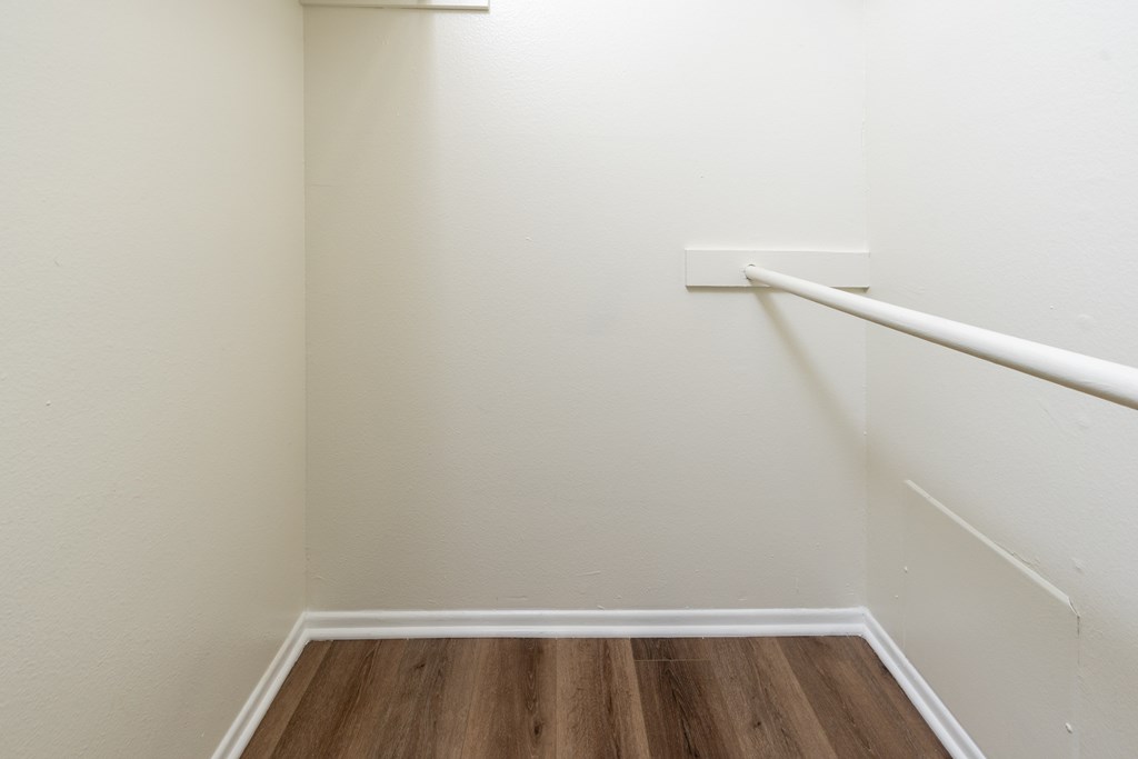 A white wall with a wooden floor and a white rail.