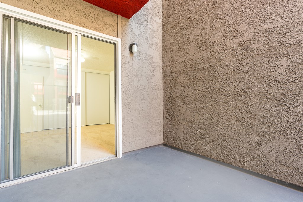 a patio with a glass door to a room on the side of a building