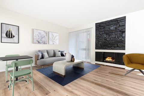 A living room with a fireplace and a grey couch.