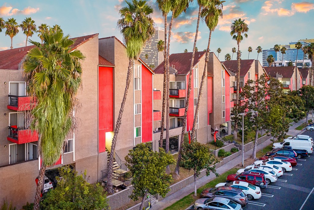 a row of townhomes with palm trees and parked cars