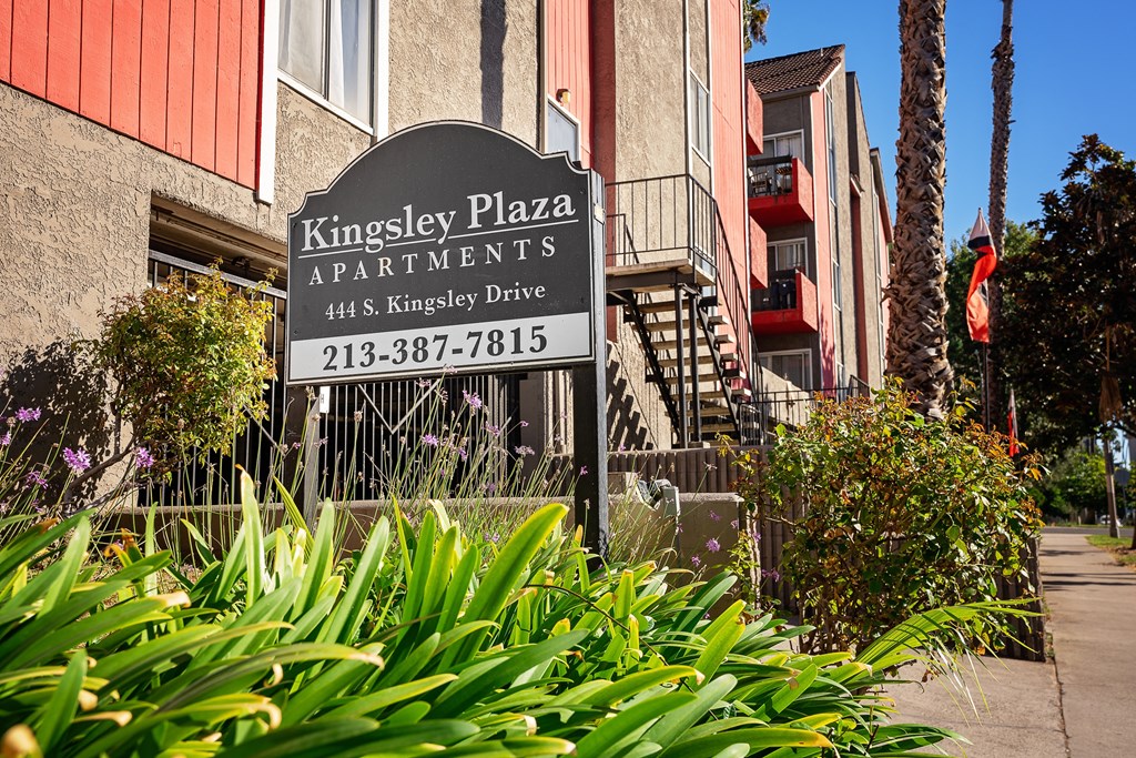 a sign for kingsley plaza apartments in front of a building