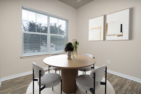 A round table with four chairs around it in a room with a window.