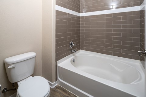 A white toilet sits next to a bathtub in a bathroom.