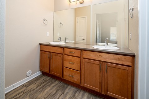 A bathroom with a wooden vanity and a large mirror.