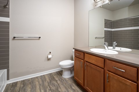 A bathroom with a toilet, sink, and wooden cabinets.